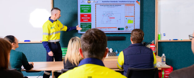 Fire Safety Advisor training in a classroom with a trainer showing safety information on a tv screen to learners in a classroom