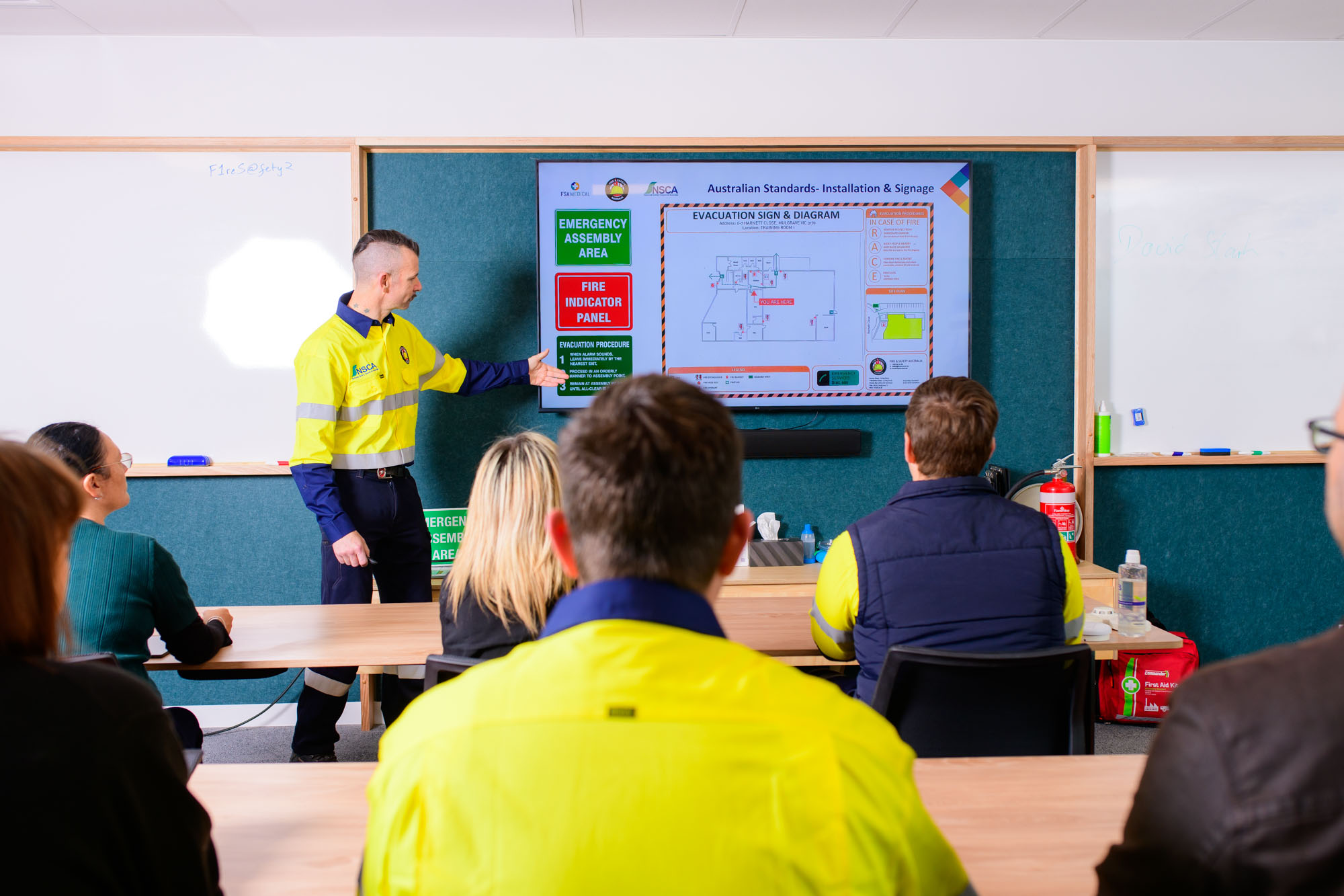 Fire Safety Advisor training in a classroom with a trainer showing safety information on a tv screen to learners in a classroom