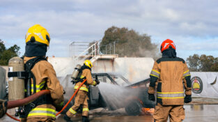 Fire Team Operations - trainees in protective turonout gear with hoses and breathing apparatus extinguishing a car fire in a training exercise