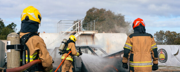 Fire Team Operations - trainees in protective turonout gear with hoses and breathing apparatus extinguishing a car fire in a training exercise